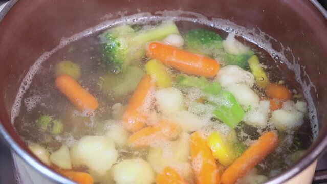 Boiling vegetarian soup with vegetables. Healthy diet food. Close up. Slow motion.