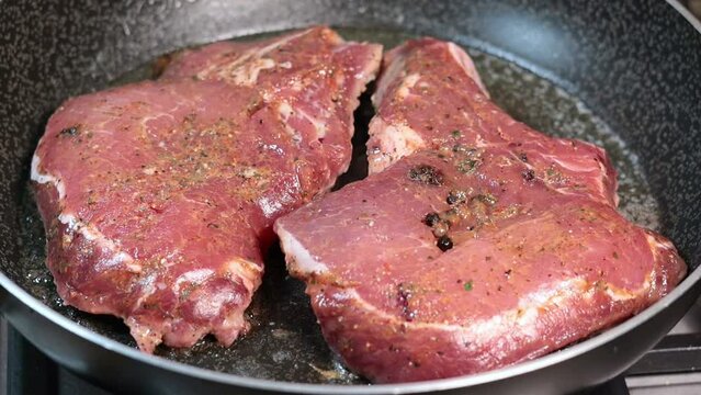 Turning fried delicious juicy pork steak on the pan. Close up, slow motion footage.