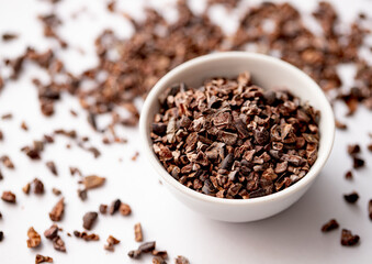 Organic Cacao Nibs in a White Ceramic Bowl. View from Above. Vegan Chocolate Concept.