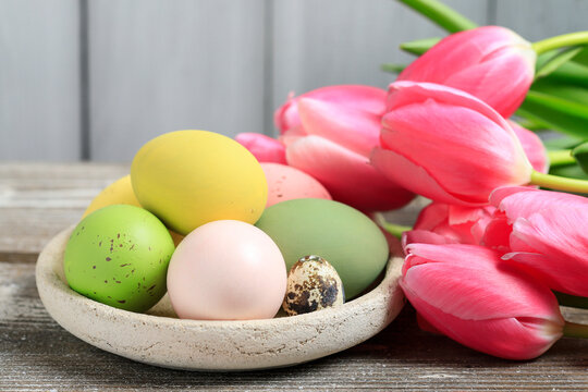 A bowl with Easter eggs and bouquet of tulips.