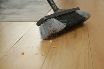 Home cleaning. Close up of woman doing housework, holding a broom and sweeping floor	
