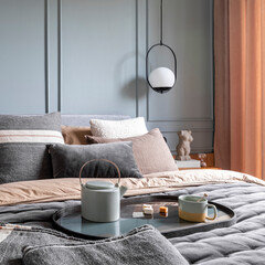 Contemporary design of bedroom interior with brown and grey bedding, pillows, bedside table, vase...