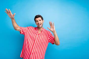 Photo of good mood positive man with bristle dressed striped shirt raising palms up sing song...