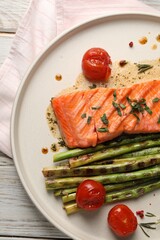 Tasty grilled salmon with tomatoes, asparagus and spices on table, top view
