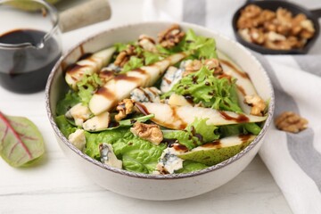Delicious pear salad with sauce in bowl on white wooden table, closeup