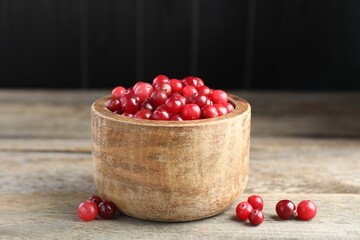 Ripe cranberries in bowl on wooden table