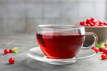 Tasty hot cranberry tea in glass cup and fresh berries on light grey textured table