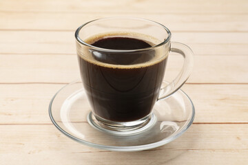 Cup of aromatic coffee on light wooden table, closeup