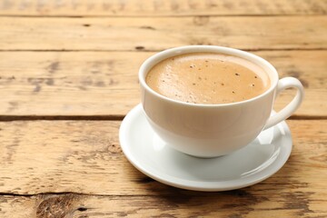 Cup of aromatic coffee on wooden table, closeup. Space for text