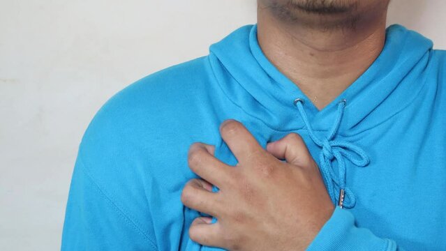 Young man with heart disease, holding hands on chest. Heart attack or stroke. risk of coronary heart disease, diabetes, hyperlipidemia, high blood pressure. isolated.