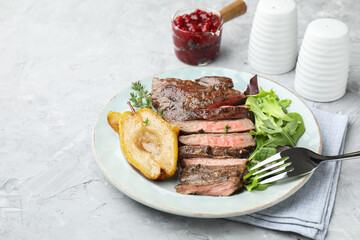 Delicious roasted beef meat, caramelized pear and greens served on light textured table. Space for text