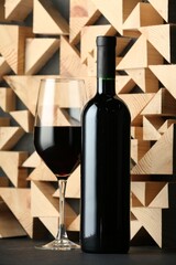 Stylish presentation of red wine in bottle and wineglass on black table