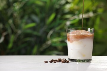 Making iced coffee at white wooden table outdoors, closeup. Space for text