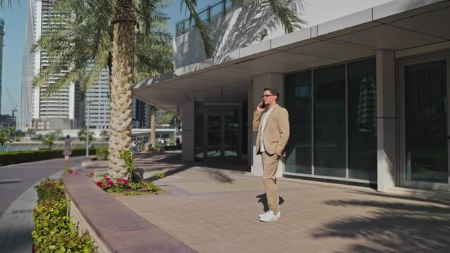 Man office worker head of company talking on phone near office building.