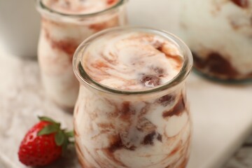 Tasty yoghurt with jam and strawberry on white marble board, closeup