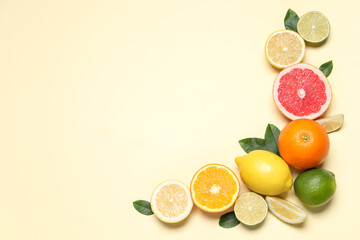 Different cut citrus fruits and leaves on beige table, flat lay. Space for text