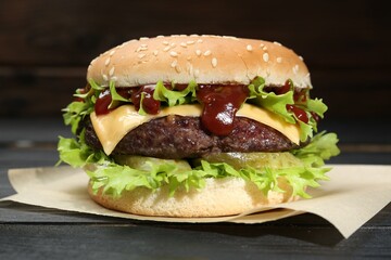 Burger with delicious patty on black wooden table, closeup