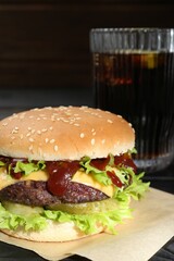 Burger with delicious patty and soda drink on table, closeup