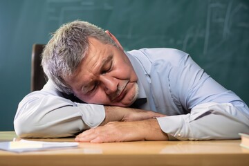 Obraz premium man sleeping in a classroom, middle-aged sleeps, elderly person asleep, person sitting down, black senior male