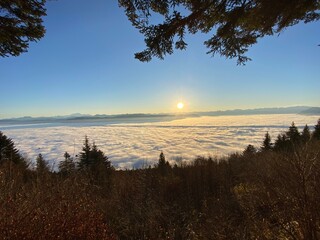 Lever de soleil avec une mer de nuages couvrant la vallée, offrant une vue spectaculaire sur des montagnes imposantes en face