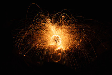 Abstract background of steel wool fireworks on Hat Chom Dao at after twilight blue hour, Showers of glowing sparks from spinning steel wool, Na Tan, Na Tan District, Ubon Ratchathani, Thailand
