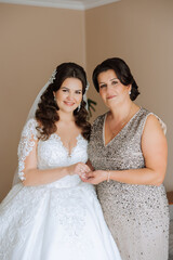 A beautiful and happy mother and her daughter, the bride, are standing next to each other. The best day for parents. Tender moments at the wedding.