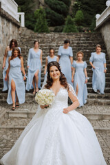 Wedding photography. A brunette bride in a white dress with a bouquet and her brunette girlfriends
