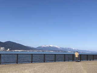 冬の海沿いから見る遠景の街の奥に見える山