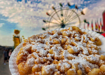 Funnel Cake with powered sugar in the foreground of a county fair Ferris wheel