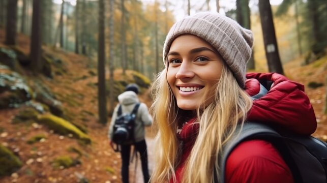 Woman with her multiethnic friends walking in woods. Smiling Female enjoying in hiking with hikers on wild trail among green trees.