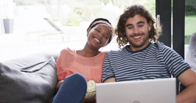 Diverse couple, a young African American woman and a young Caucasian man, watching a movie on a lapt