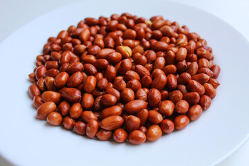 Fried groundnut, Goober or Monkey Nut, or Arachis hypogaea. On a white plate, isolated on white background