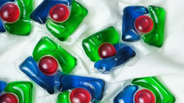 Lots of laundry pods on satin fabric close-up top view