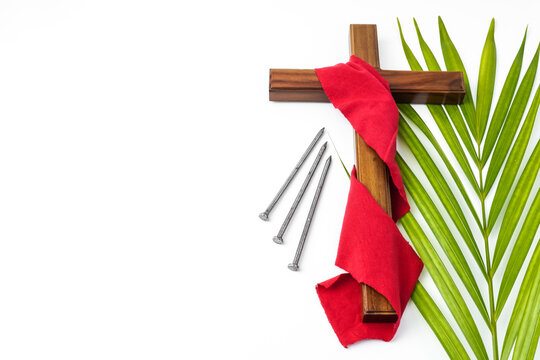 Jesus Wooden cross wrapped with red cloth with nails and palm leaves. Catholic Christians Good Friday Ceremony. Isolated on white background with empty blank copy text space.