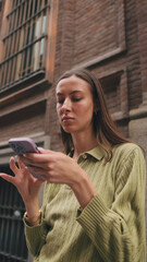 Fototapeta premium Close-up of a young woman using a mobile phone on the street of a European city