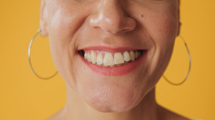 Detailed close-up shot of woman's smile isolated on yellow background
