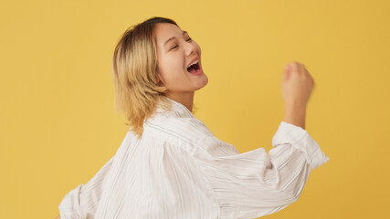 Fototapeta premium Young woman dancing isolated on yellow background in studio