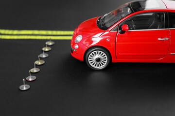 Pins as barrier blocking way for red toy car. Development through obstacles overcoming
