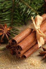 Different aromatic spices and fir branches on wooden table, closeup