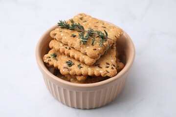 Cereal crackers with flax, sesame seeds and thyme in bowl on white table, closeup
