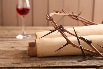 Crown of thorns, old scrolls and glass with wine on wooden table, selective focus