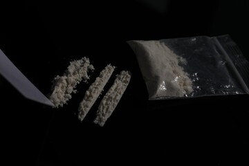 Drug addiction. Plastic bag with cocaine and blank card on black table