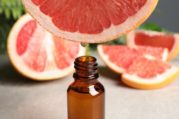 Dripping grapefruit juice from fruit into bottle at table, closeup