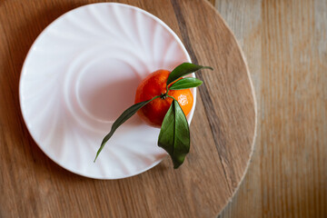Mandarin or orange on white plate. Citrus clementine with green leaves. Ready to eat tangerine on...