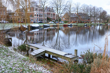 Picturesque view of water canal with moored boats in city on winter day