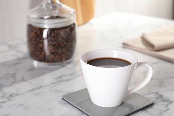 Delicious coffee in cup on white marble table, closeup. Space for text