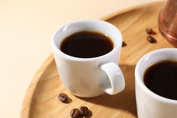 Delicious coffee in cups and beans on beige table, closeup