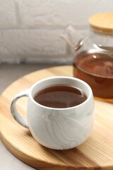 Aromatic tea in cup and glass teapot on table, closeup