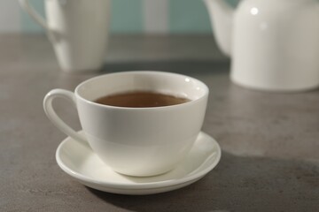 Aromatic tea in cup on gray table