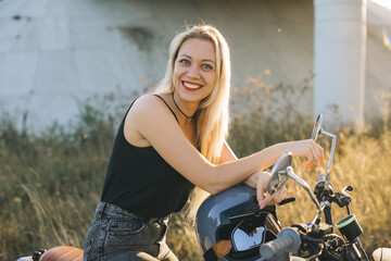 Biker girl sits on a motorcycle. Young beautiful blonde woman sitting on a motorcycle on the...